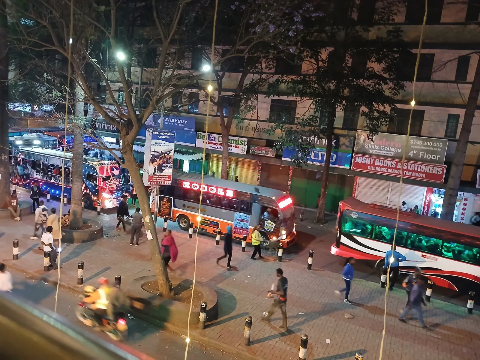 Matatus and a bus at a busy evening stage on Tom Mboya Street with pedestrians and a boda rider