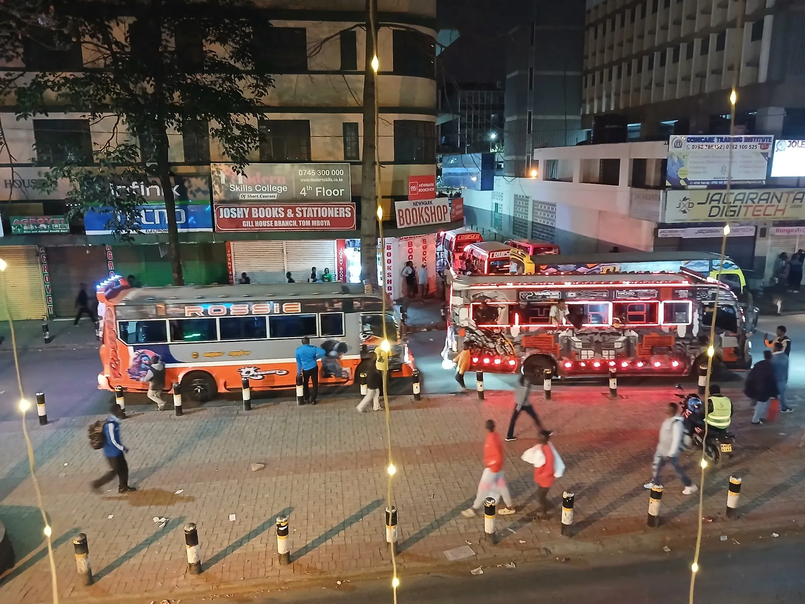 Two decorated matatus with red and blue lights at an evening stage on Tom Mboya Street