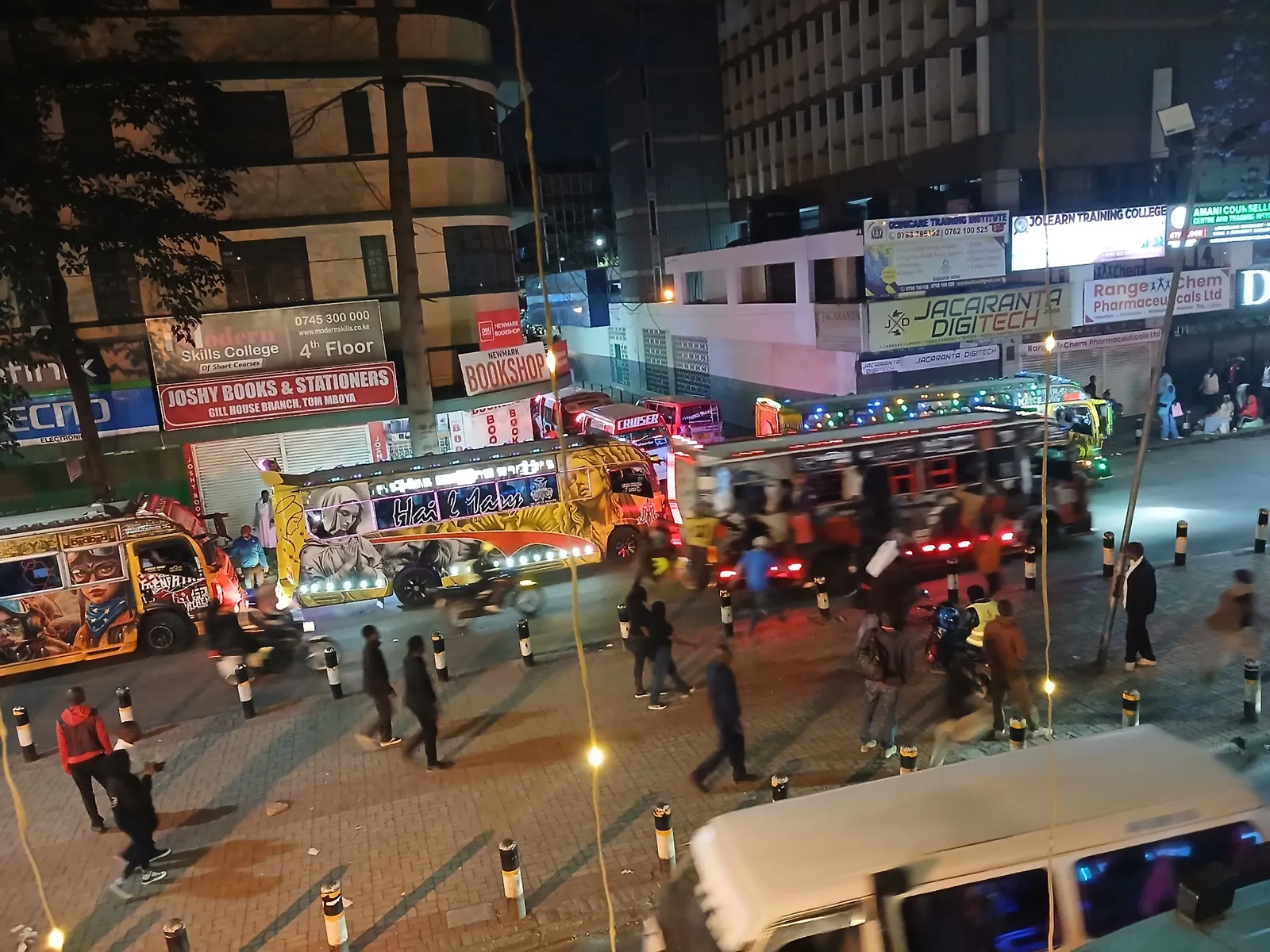 Brightly painted and lit matatus loading passengers on Tom Mboya Street, Nairobi, at night